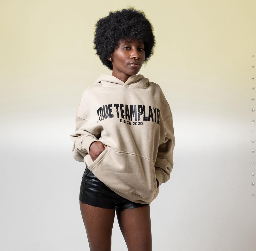 Model wearing the beige True Team Players oversized pullover hoodie