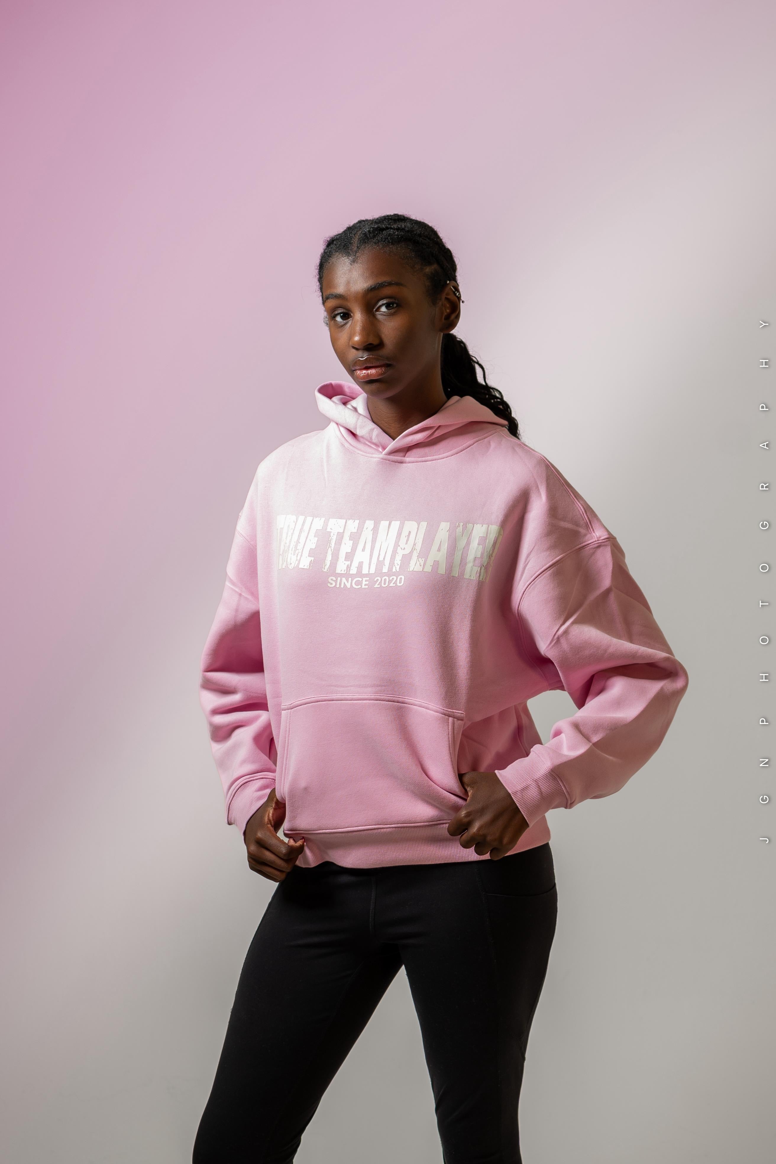 Model wearing the pink True Team Players oversized pullover hoodie